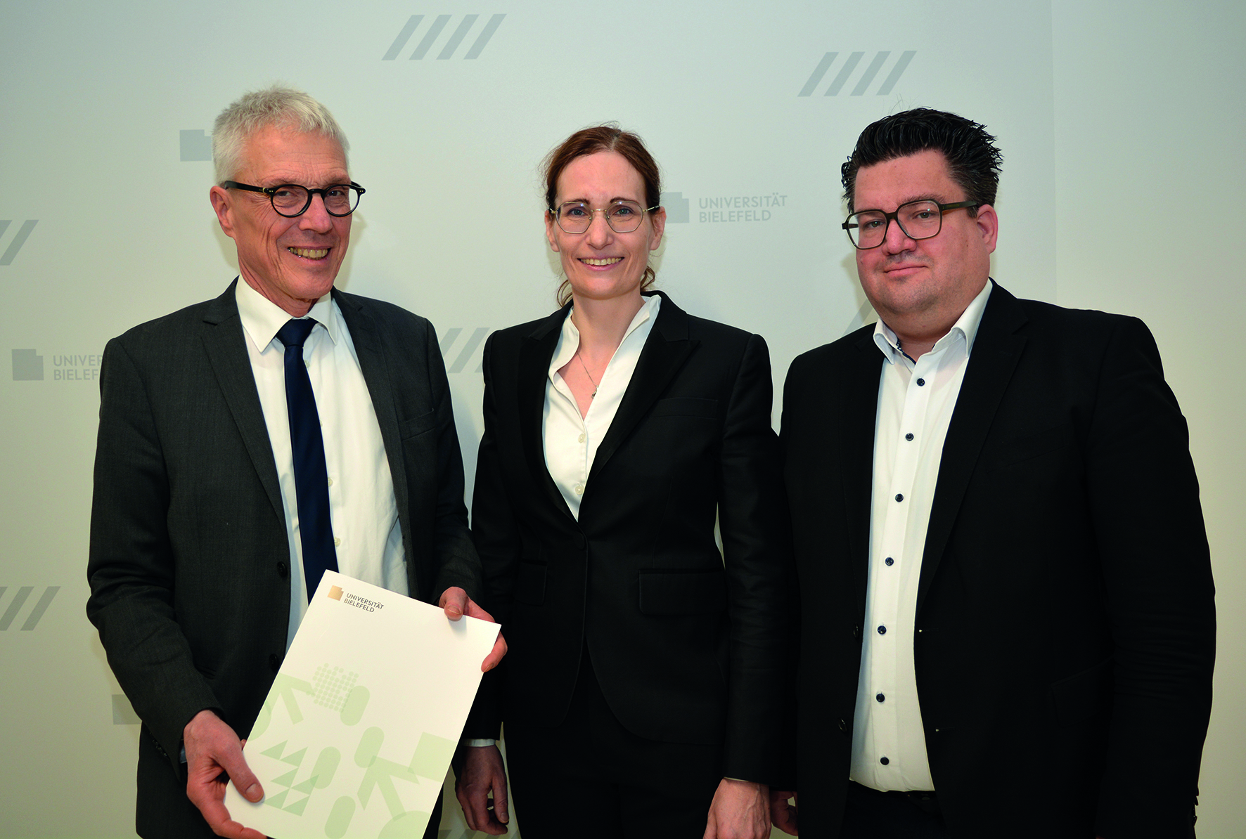 Der Kanzler der Universität Bielefeld Dr. Stephan Becker (l.) übergibt Univ.-Prof. Dr. Claudia Scherl (Mitte) ihre Ernennungsurkunde im Beisein von Bernd Henkemeier, kaufmännischer Direktor des Klinikum Bielefeld (r.).