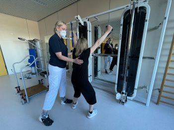 Bild Patientin und Physiotherapeutin bei einer Übung an einem Fitnessgerät Bild Patientin und Physiotherapeutin bei einer Übung an einem Fitnessgerät